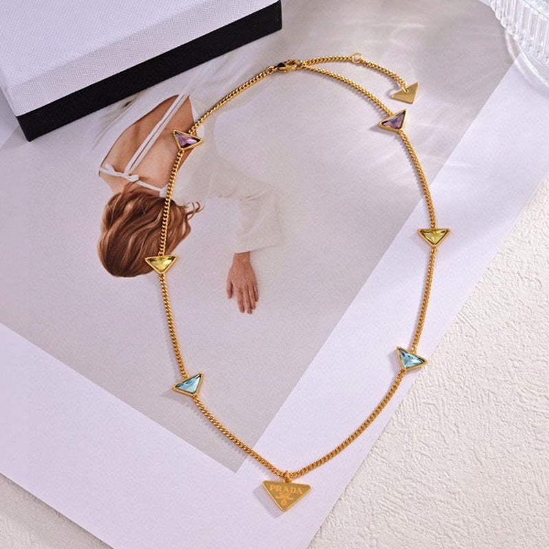 Gold necklace with triangular pendants on a white surface