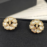 Gold earrings with heart-shaped gemstones on a black stand.