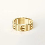 Gold ring with Cartier branding on a light beige background