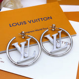 Silver earrings with 'LV' logo on a Louis Vuitton background