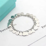 Silver bracelet with heart-shaped charms on a white surface with Tiffany & Co. branding.